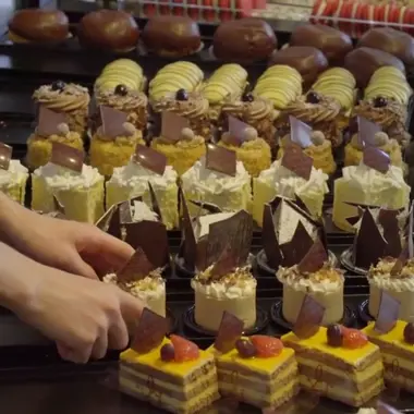Student plaatst zorgvuldig verschillende soorten gebak ter presentatie in een winkel voor bakkerij en winkelambacht