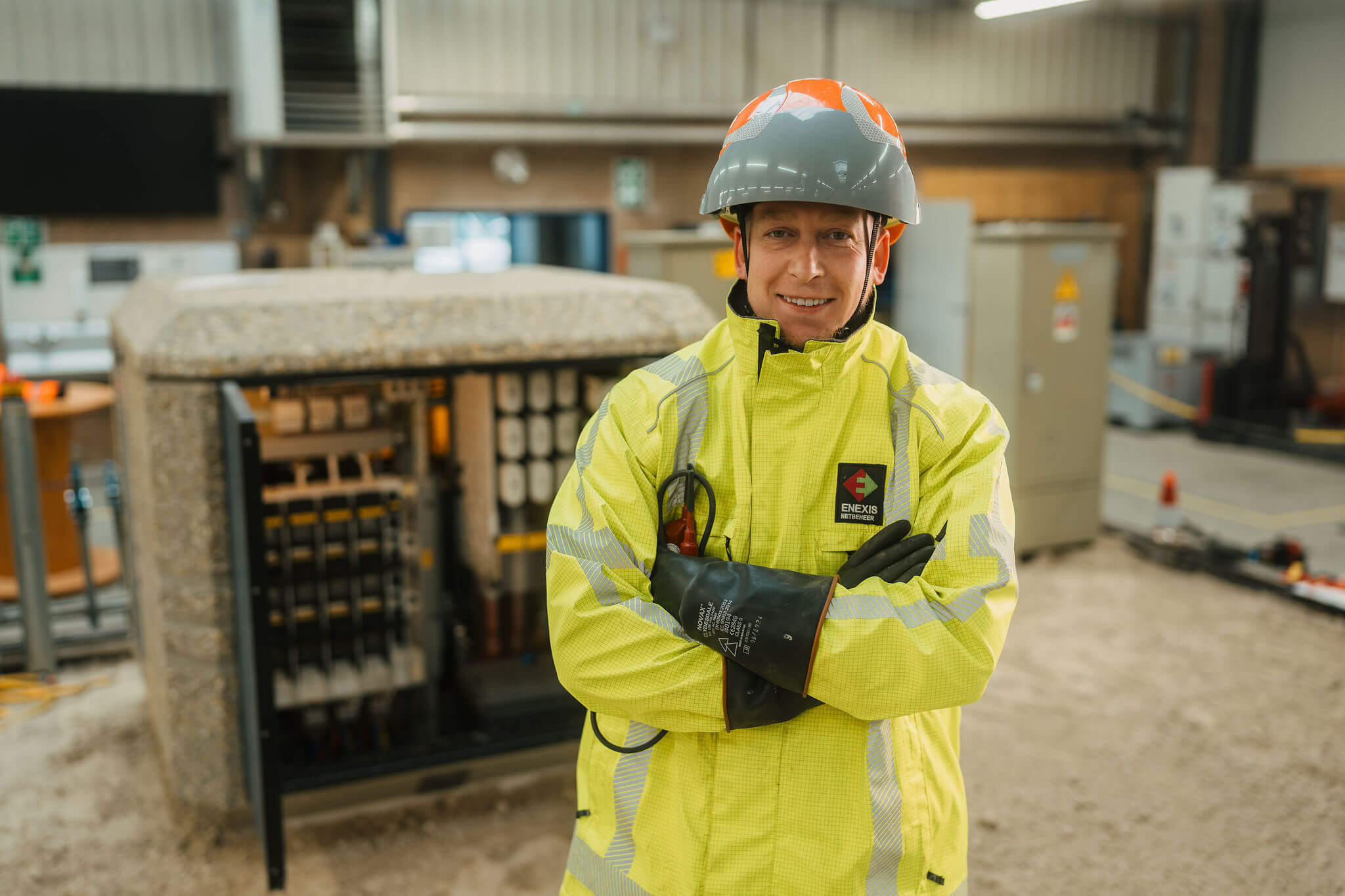 Elektrotechnicus infra in beschermende kleding staat in werkplaats bij elektrische installatie