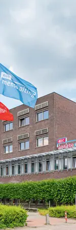 Hoofdgebouw van ROC Menso Alting in Groningen met vlaggen en een duidelijke ingang aan Gedempte Kattendiep.