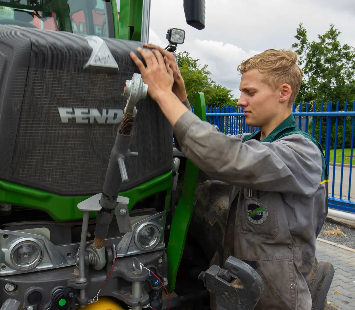 Technisch specialist onderzoekt en repareert mechanische onderdelen van een landbouwvoertuig buiten bij een werkplaats