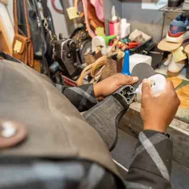 Een vakman repareert schoenmateriaal met precisie in een werkplaats voor creatief vakmanschap.