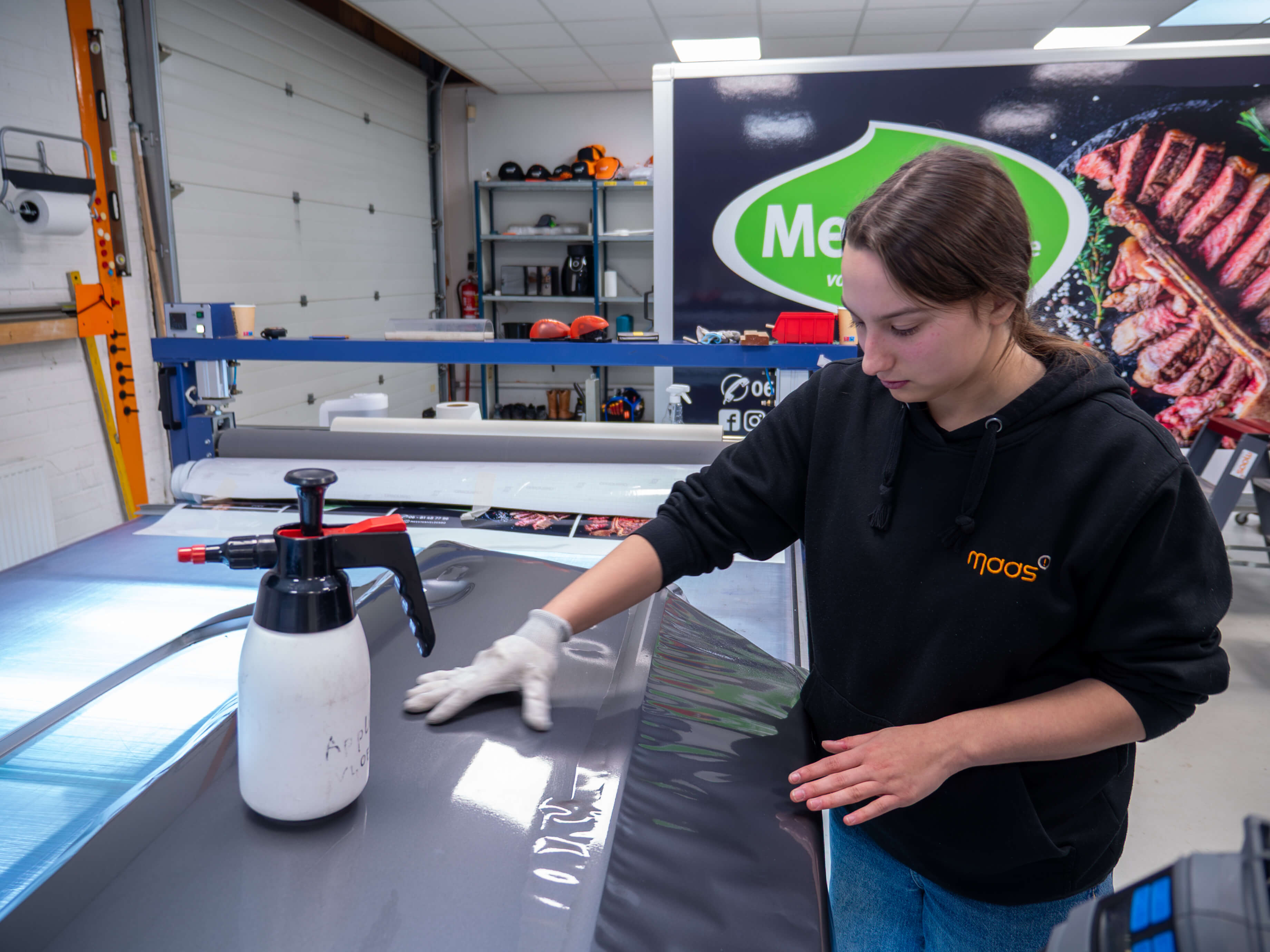 Leerling werkt nauwkeurig met folie op een hoogwaardig printproject in een praktijkgerichte leeromgeving