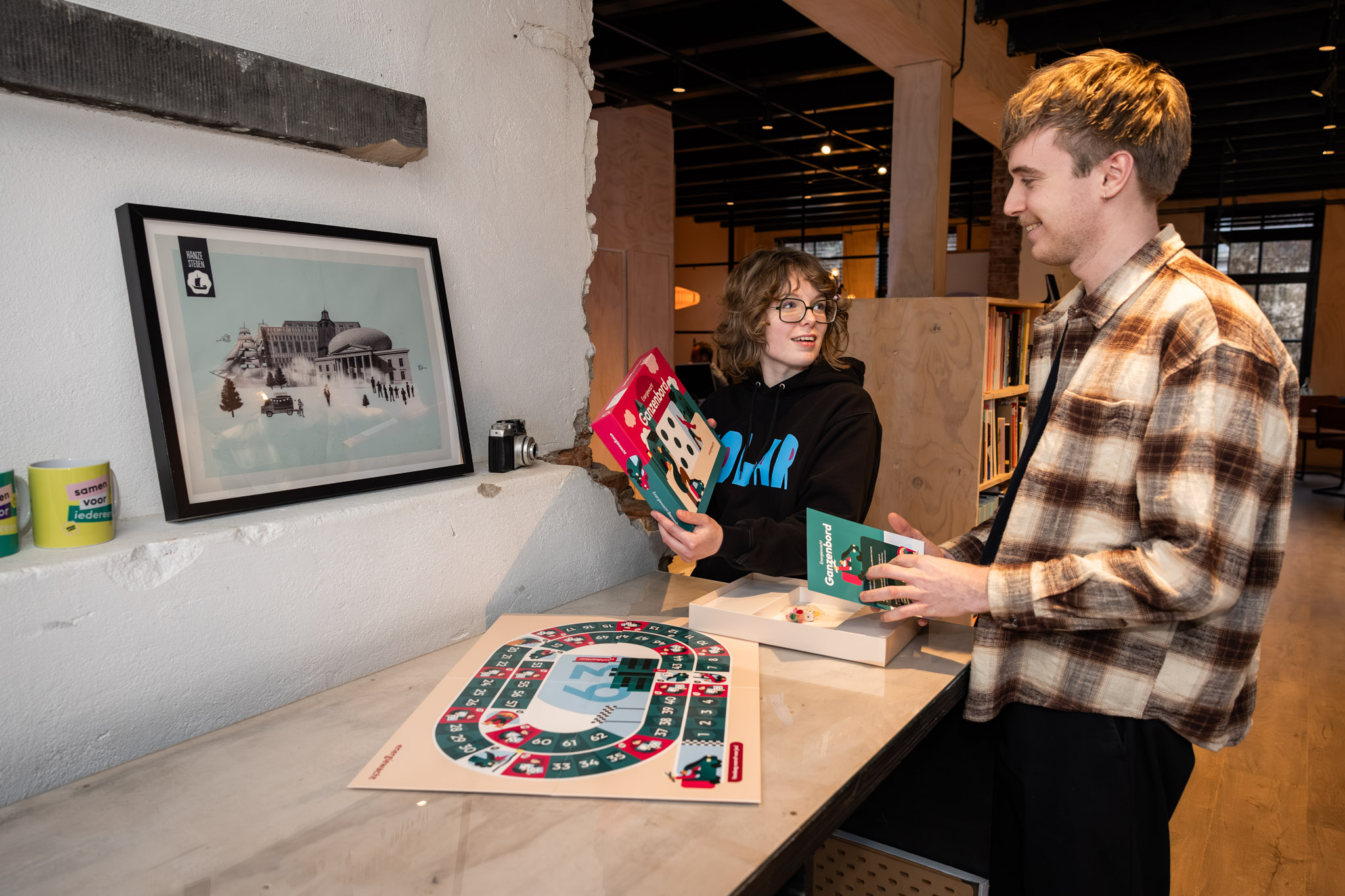Twee jongeren bespreken een bordspel en lesmateriaal in een leeromgeving.