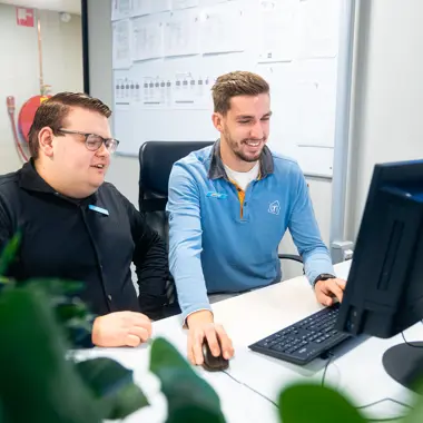 Twee medewerkers overleggen bij een computer, gericht op klantadvies en winkelbeheer