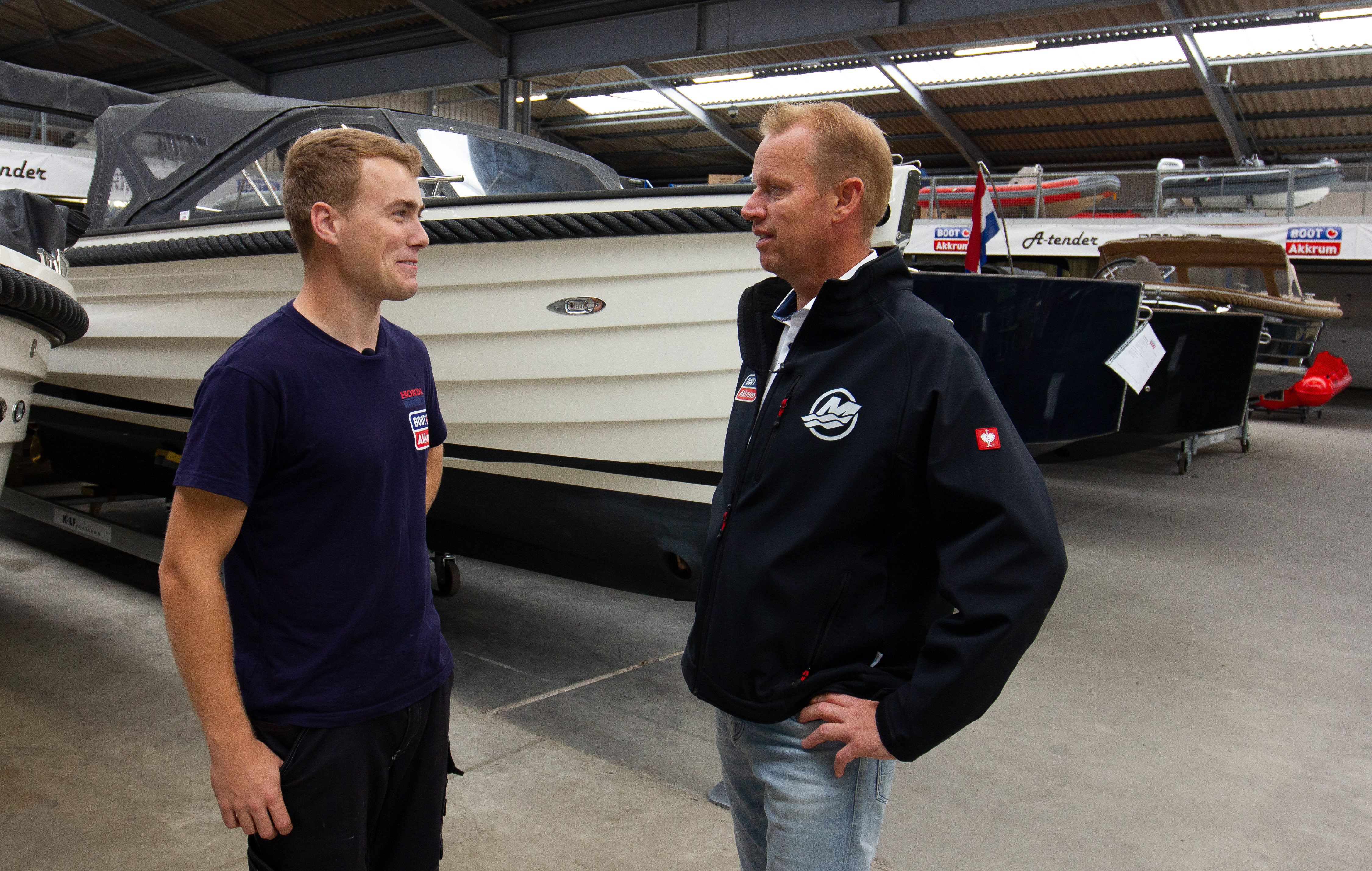 Twee mannen bespreken technische aspecten van boten in een werkplaats voor maritieme opleidingen.