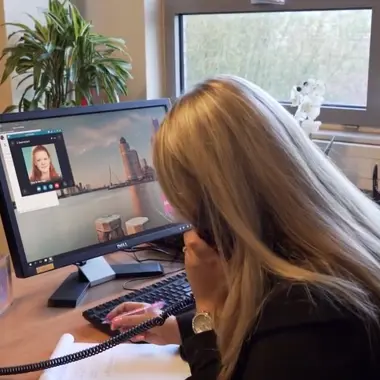 Student beheert kantooradministratie en plant afspraken aan bureau met computer en telefoon