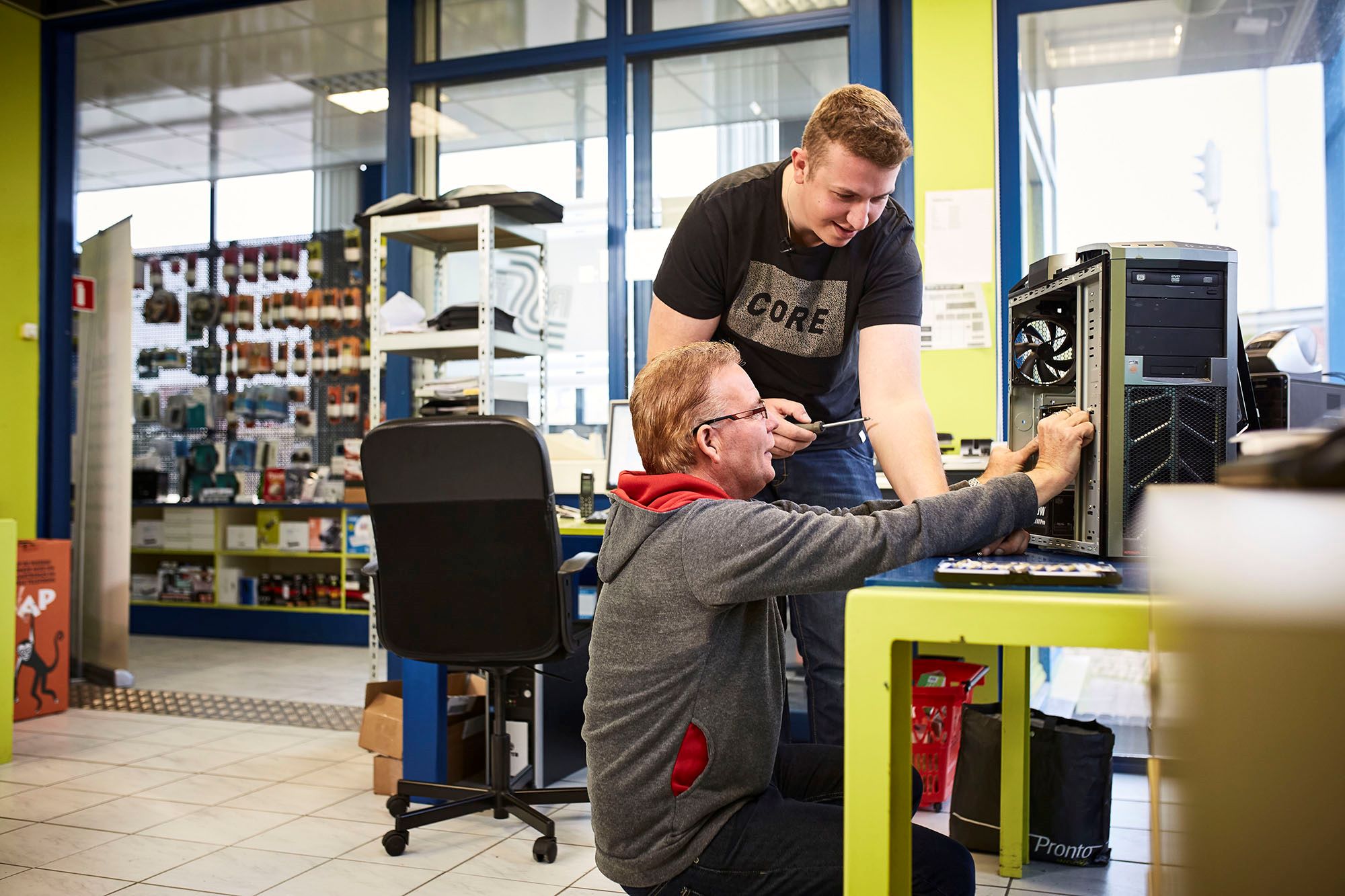 Technisch medewerker ondersteunt collega bij het bouwen en onderhouden van een computersysteem in een werkplaats