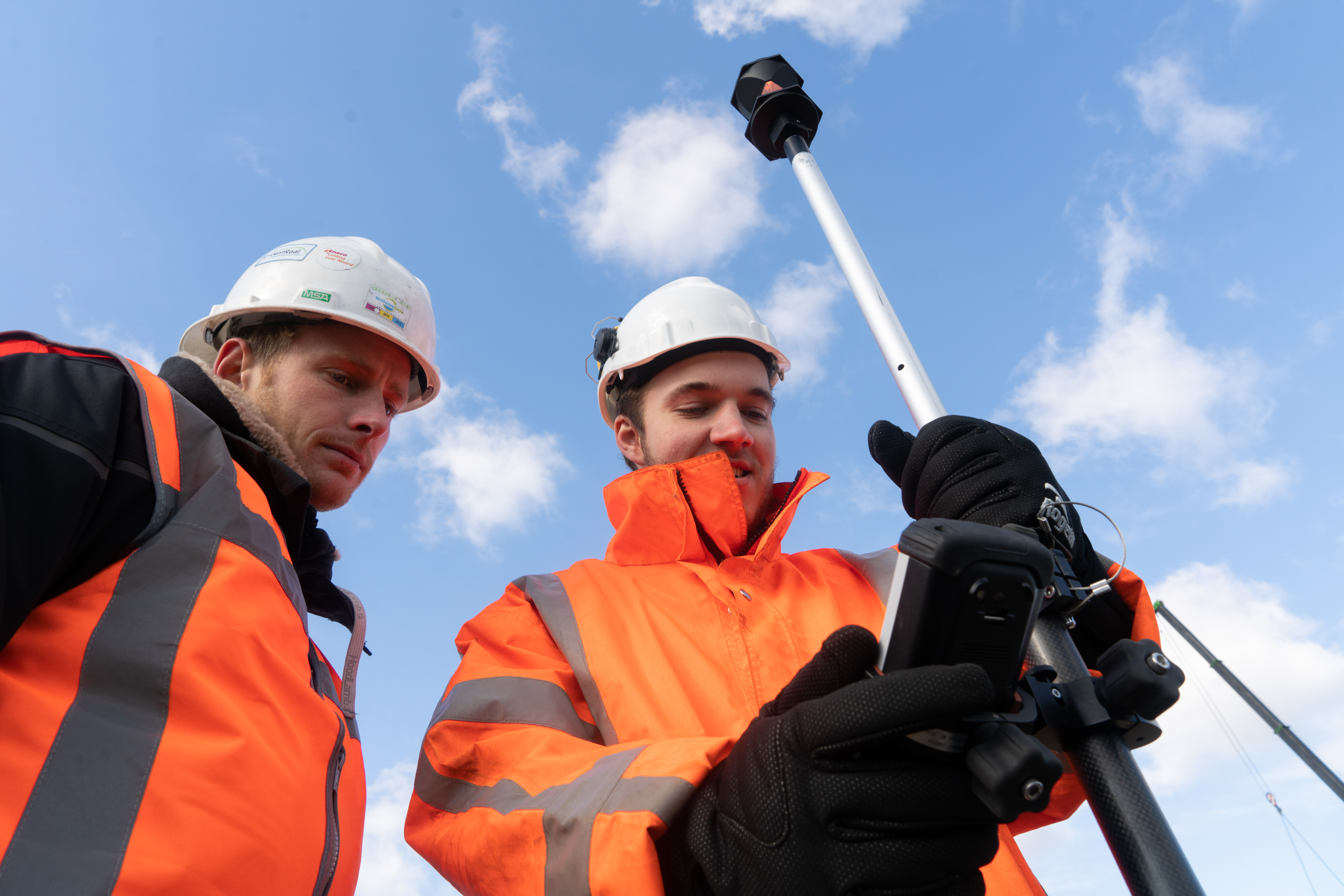 Studenten techniek meten land met digitale apparatuur buiten tijdens landmeetkunde opleiding