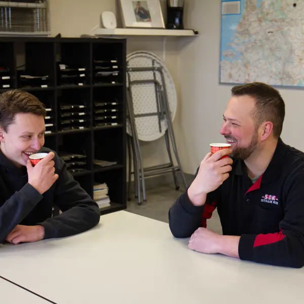 Twee mensen voeren een ontspannen gesprek tijdens een koffiepauze in een werkruimte.