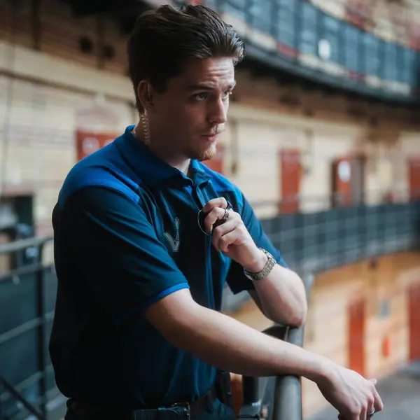 Beveiliger houdt communicatiemiddel vast en observeert een openbare ruimte met meerdere verdiepingen.