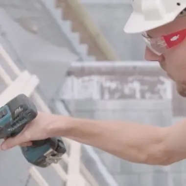 Monteur gebruikt accuboormachine op een bouwplaats met materialen voor woningbouw