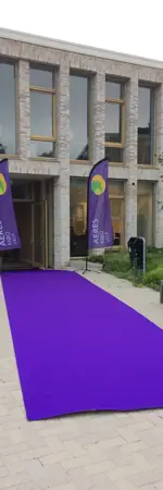 Ingang van onderwijsgebouw met paarse lopers en vlaggen van Aeres MBO Velp