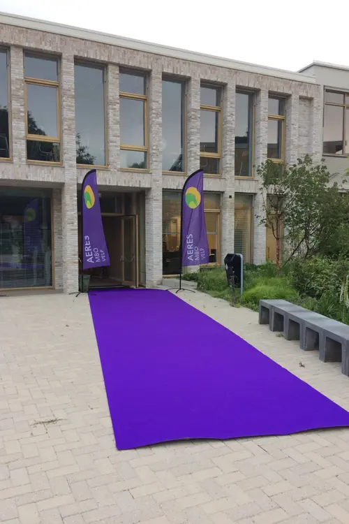 Ingang van onderwijsgebouw met paarse lopers en vlaggen van Aeres MBO Velp