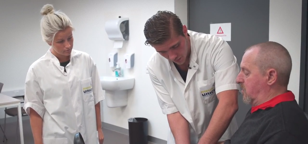 Zorgstudenten oefenen verpleegtechnische vaardigheden bij een zorgvrager in een praktijkomgeving