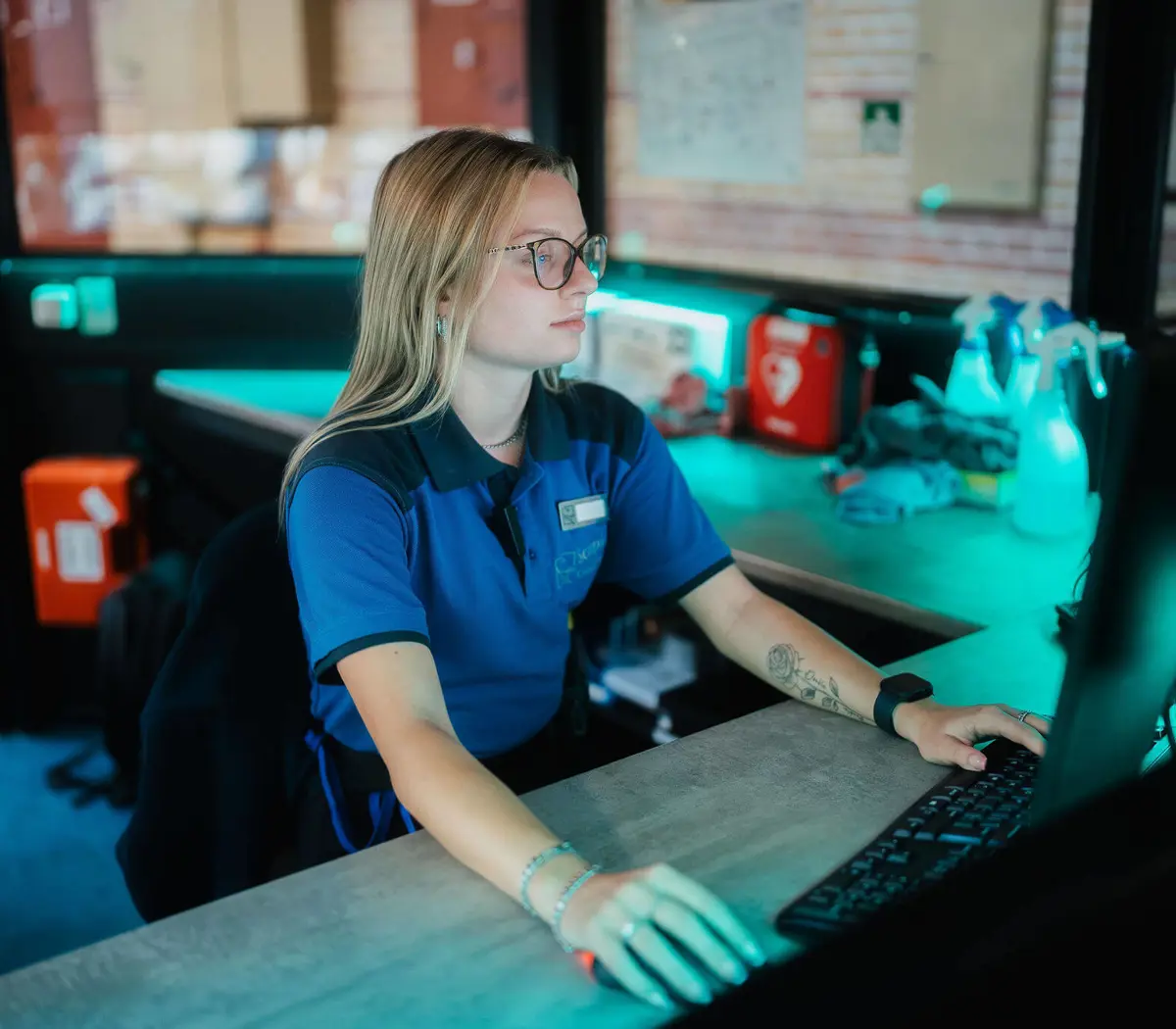 Beveiliger aan het werk achter een controlepaneel in een beveiligde omgeving, geconcentreerd op taak.