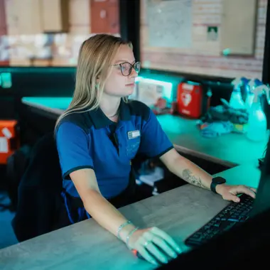 Beveiligingsmedewerker monitort camerabeelden om veiligheid te waarborgen in gebouw.