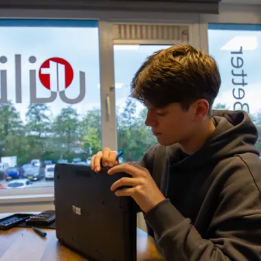 Student onderzoekt een laptop om technische problemen op te lossen en digitale vaardigheden te ontwikkelen.