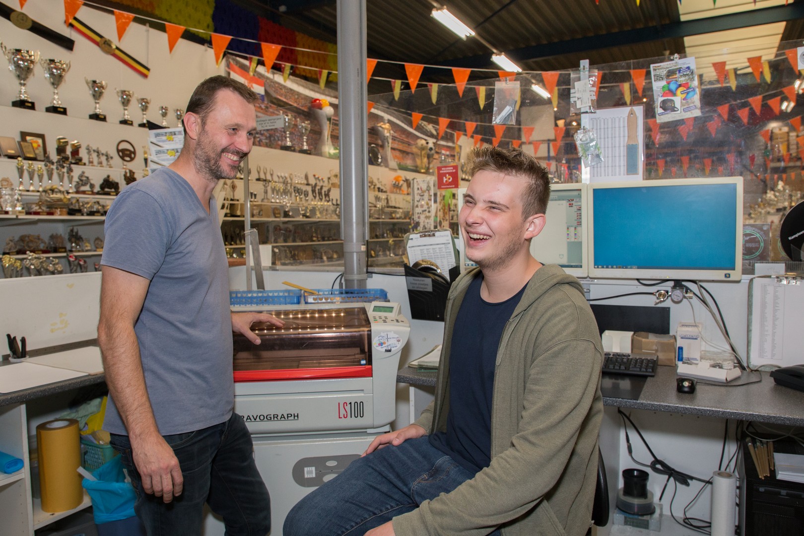 Twee studenten die samenwerken in een werkplaats met apparatuur voor reclameproductie