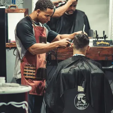 Kapper werkt geconcentreerd aan een moderne herenkapsel tijdens praktijkles uiterlijke verzorging