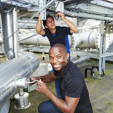 Technische vakmensen controleren en onderhouden leidingen in een industriële omgeving.