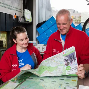 Medewerkers bespreken een kaart en informatiebrochure over recreatieactiviteiten.