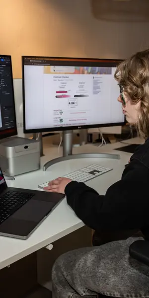 Student werkt met ontwerpsoftware op laptop en schermen tijdens mediavormgever opleiding