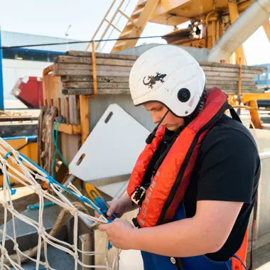 Scholier scheepswerktuigkunde controleert netten aan boord van een schip tijdens praktijkles