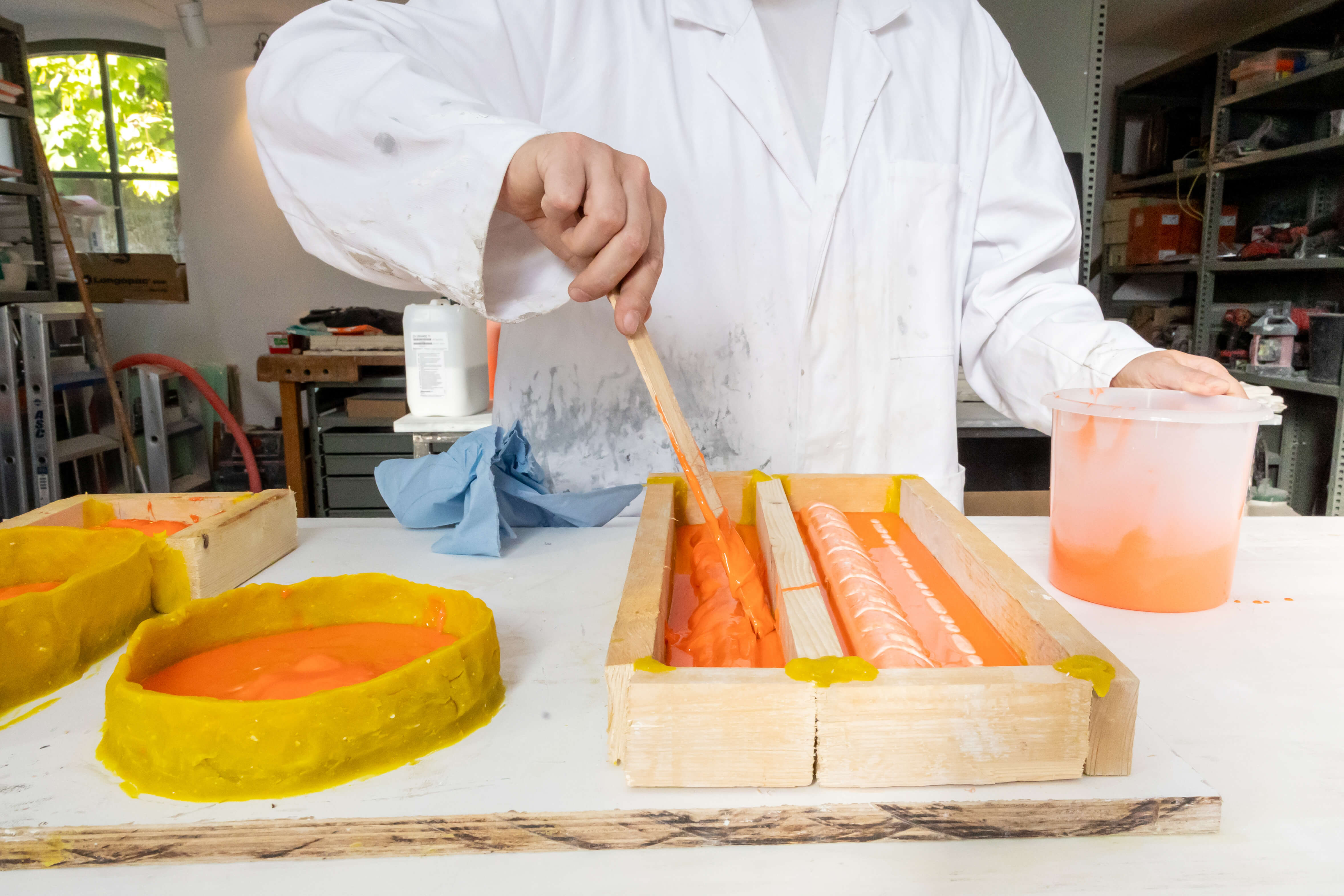 Student volgt praktijkles decoratieve techniek met het aanbrengen van gekleurd pleisterwerk in een werkplaats
