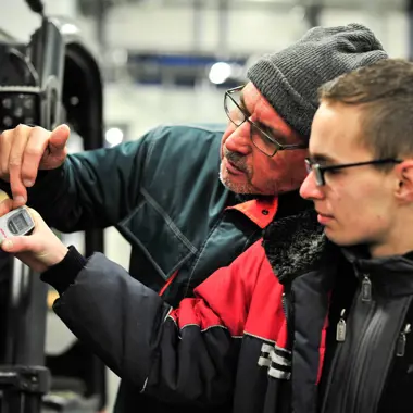 Medewerker en leerling controleren uitrusting voor transport in maritieme logistiek.