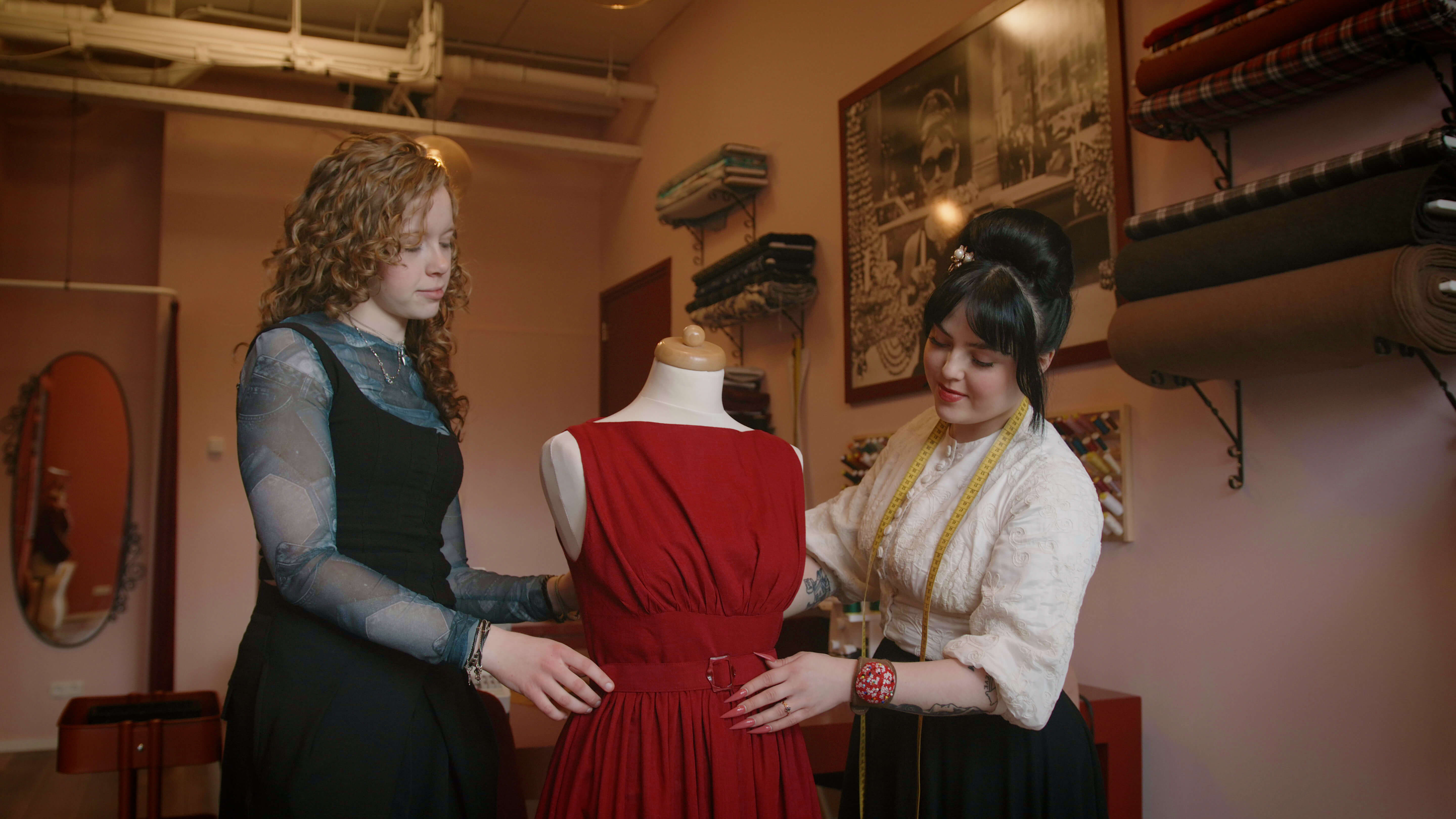 Twee vakspecialisten ondernemen samenwerken bij het ontwerpen en aanpassen van een kledingstuk in een atelier.