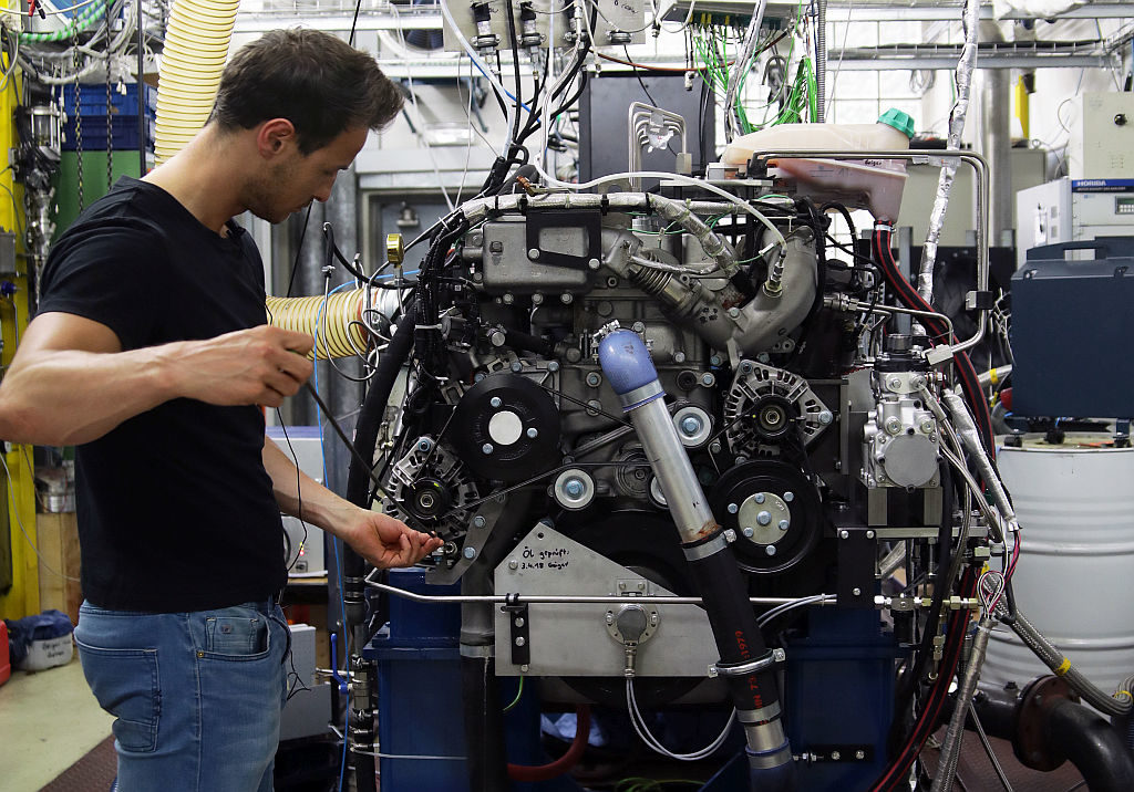 Technisch specialist test en stelt een verbrandingsmotor in in een werkplaats met apparatuur.