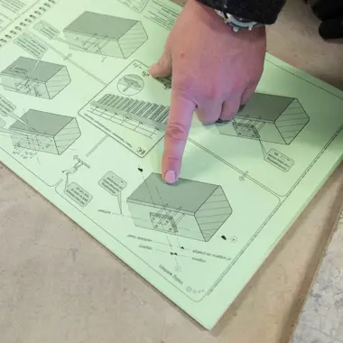 Hand wijst op bouwtekening met gedetailleerde plattegrond van woningen voor gespecialiseerde aanneming.