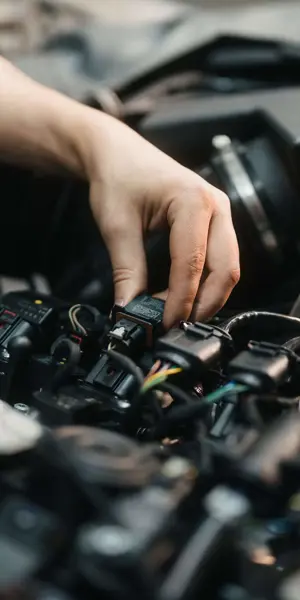 Technisch specialist onderzoekt en repareert onderdelen in motorruimte van verschillende voertuigen