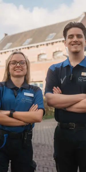 Twee beveiligers in uniform staan met armen gekruist voor een historisch gebouw en stralen zelfvertrouwen uit.