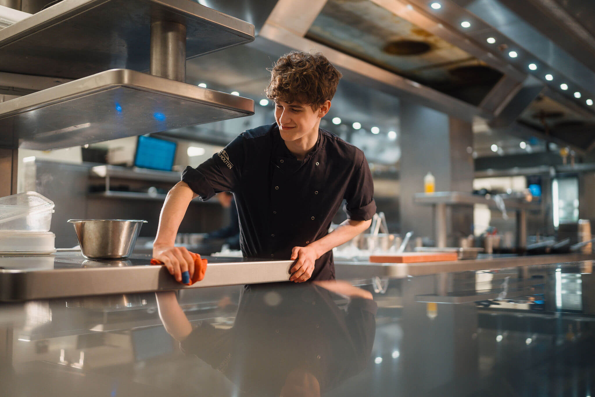 Een kok maakt het werkblad schoon in een professionele keuken tijdens de opleiding horeca.