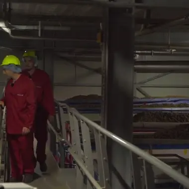 Medewerkers in beschermende kleding controleren en bedienen apparatuur in een procesindustrieomgeving